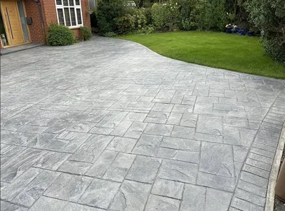 Grey pattern imprinted concrete driveway with a slate-effect finish, running up to a front door