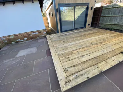 Timber deck in front of a garden room, set on sandstone paving