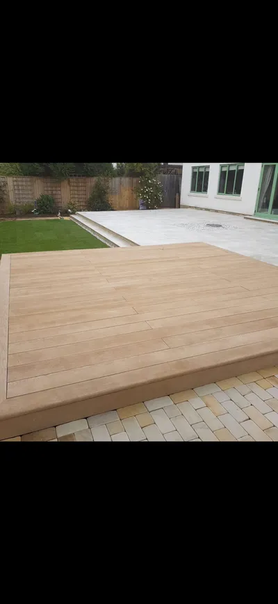 Composite deck beside a porcelain patio and block paving