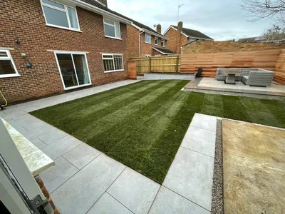 Landscaped garden with a striped lawn, porcelain patio, cedar slatted fence and a raised seating area