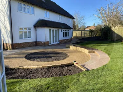 Garden with a gravel circle, sleeper raised beds and curved steps up to the lawn
