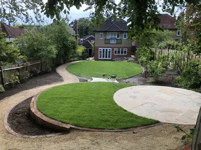 Long garden with circular lawns, gravel paths and a round sandstone patio