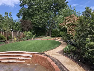 Finished garden with a lawn, gravel path, curved brick steps and mature trees
