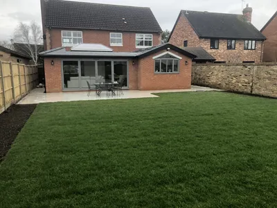 Large newly turfed lawn with a patio by the house