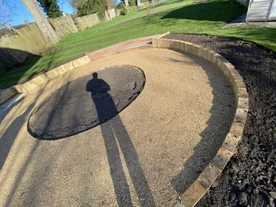 Circular gravel terrace edged with a timber sleeper retaining wall