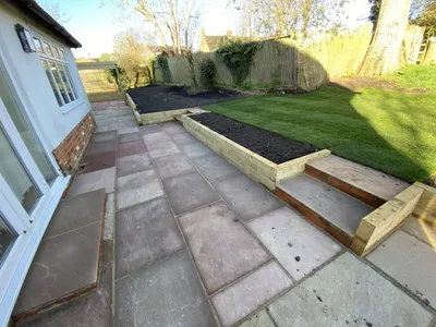 Sandstone patio with steps and timber sleeper raised beds