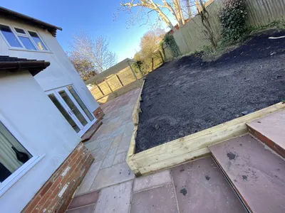 Sandstone paving path beside a sleeper-edged planting bed