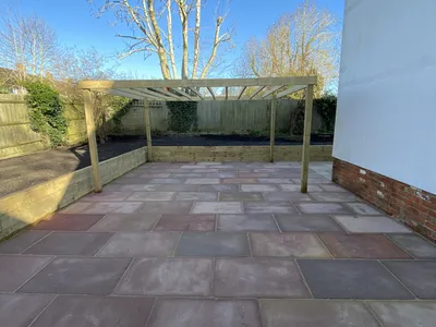 Sandstone patio with a timber pergola and sleeper raised beds