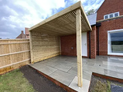 Timber slatted pergola over a sandstone patio next to the house