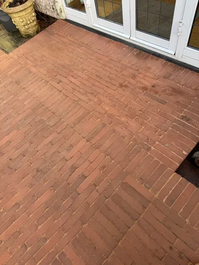 Red brick block paving laid in a herringbone pattern outside white French doors