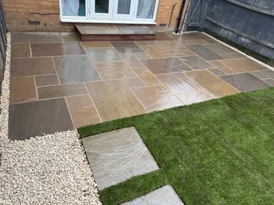 Riven paving patio outside French doors, meeting a new lawn and stepping stones